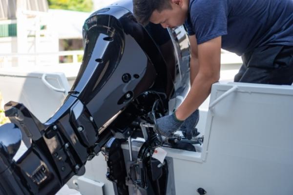 Marine Mechanic working on an aluminum boat with an outboard engine